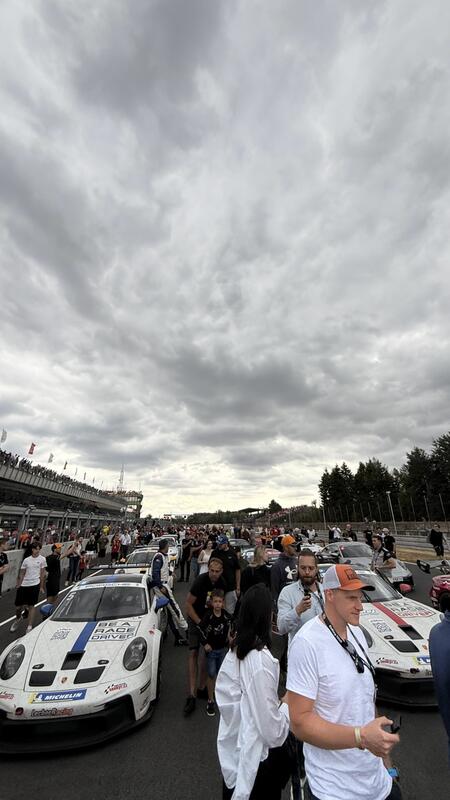 Davy fanoušků procházející se po dráze mezi vozy Porsche...
